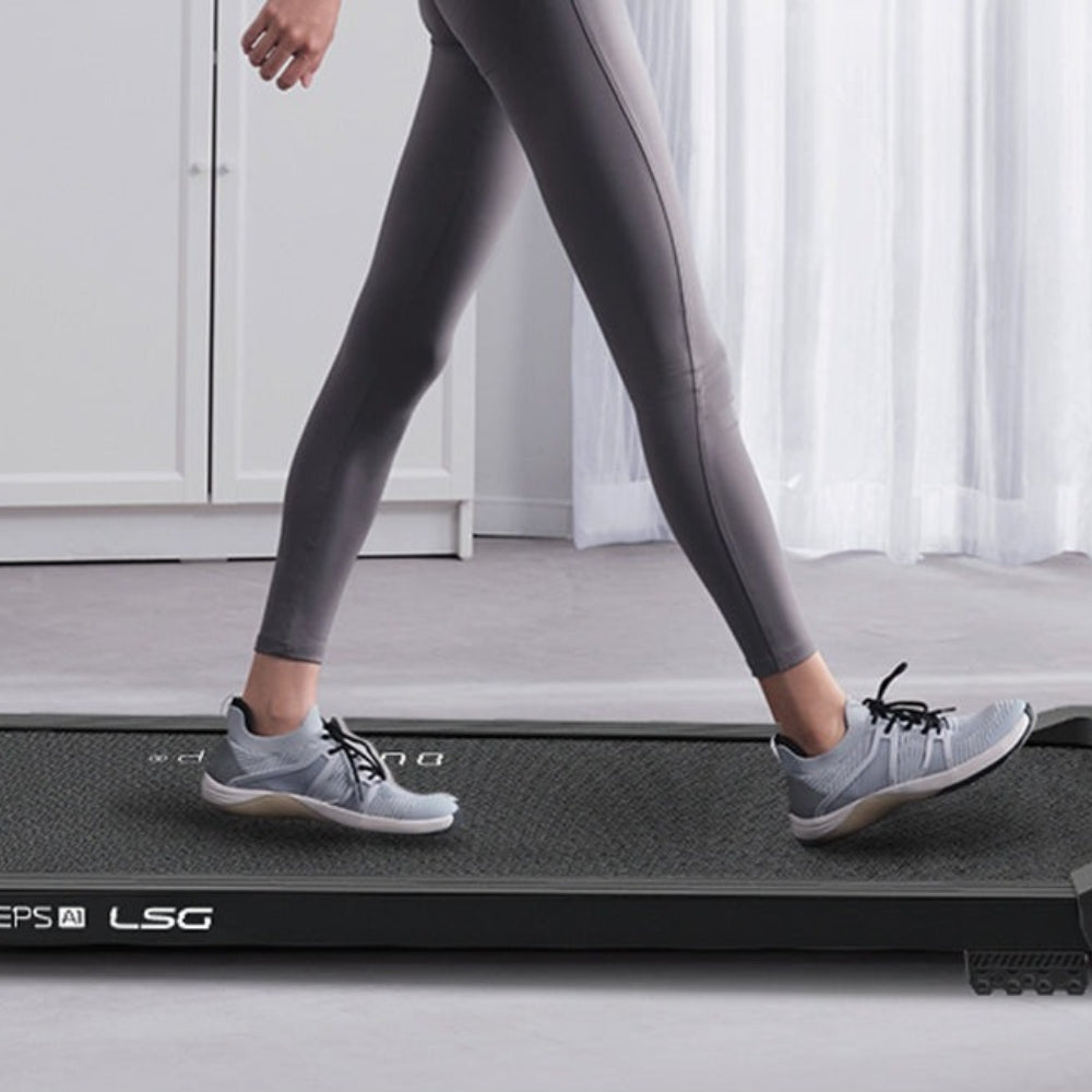 Woman walking on a sleek, modern treadmill in stylish activewear for home fitness